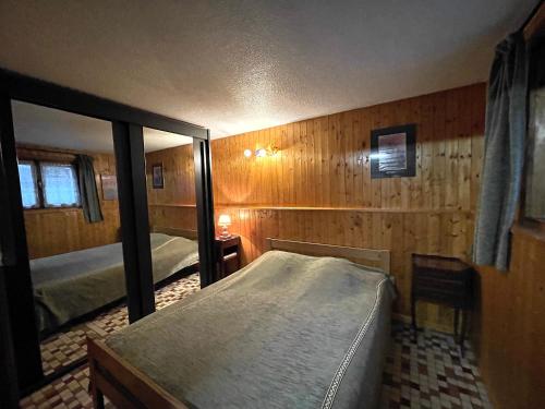 une chambre avec deux lits et un grand miroir dans l'établissement GENTIANES 0-Studio basic proche pistes 4 pers, à La Clusaz
