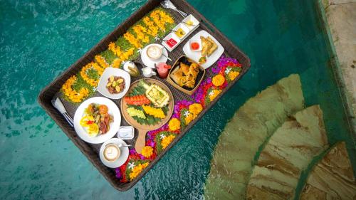 ein Tablett mit Essen auf einem Wasserbecken in der Unterkunft Kawi Resort in Tegalalang