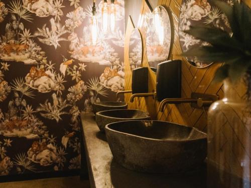 a row of sinks in a bathroom with floral wallpaper at The Orpen Kruger in Welverdiend