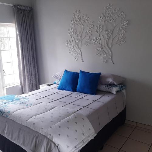 a bedroom with a large bed with blue pillows at The Cradle's Rest Guest House in Krugersdorp