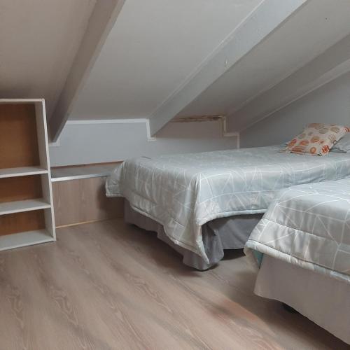 a attic bedroom with two beds and a book shelf at The Cradle's Rest Guest House in Krugersdorp