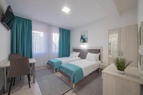 a hotel room with two beds and a desk at AS APARTMANI PIROT in Pirot