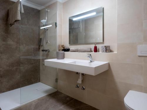 een badkamer met een wastafel en een douche met een spiegel bij Jagerwirt rooms in Völkermarkt