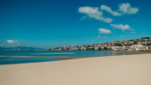 a view of a beach with a town in the background at Hotel Bienestar Moaña in Moaña