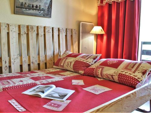 リスルにあるAppartement Risoul, 1 pièce, 4 personnes - FR-1-330-91の赤毛布と本が敷かれたベッド