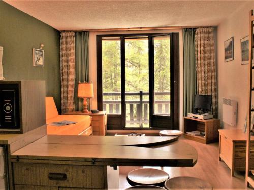 a living room with a table and a large window at Studio 4 couchages à Risoul 1850 - pied de pistes, calme, balcon exposé Sud - FR-1-330-58 in Risoul
