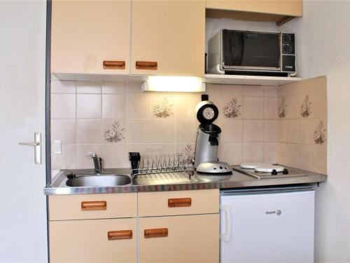 une petite cuisine avec un évier et un micro-ondes dans l'établissement Appartement studio cosy à Risoul - Idéalement situé, 4 couchages - FR-1-330-126, à Risoul