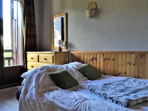 a bed with two green pillows on it in a bedroom at Studio 4 pers avec balcon - Animaux admis - Parking gratuit - FR-1-330-131 in Risoul