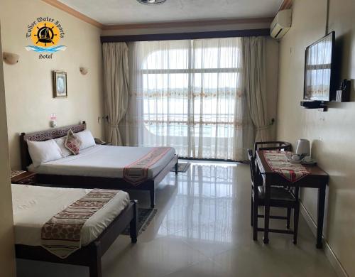 a bedroom with two beds and a desk and a window at Tudor Water Sports Hotel in Mombasa