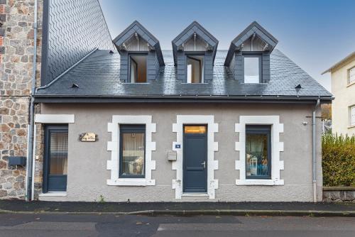 a gray house with white windows and a blue door at Le Cosy de Claire in La Bourboule