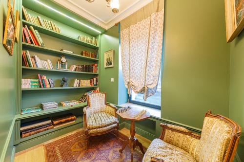 a library with two chairs and a table and a window at Le Cosy de Claire in La Bourboule