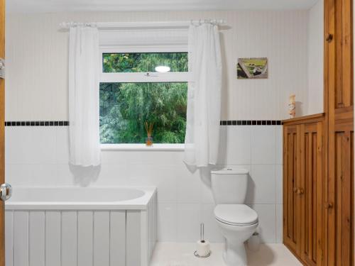 a bathroom with a tub and a toilet and a window at Pass the Keys Cosy Home in the Idyllic Duddon Valley in Ulpha