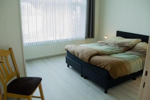 a bedroom with a bed and a chair and a window at Vakantiehuis Oostendorp in Winterswijk-Meddo