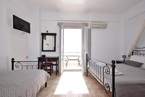 a bedroom with two beds and a desk and a window at Anessis in Fira