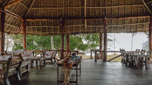 a restaurant with tables and chairs and a large pavilion at Pemba Eco Lodge in Kengeja