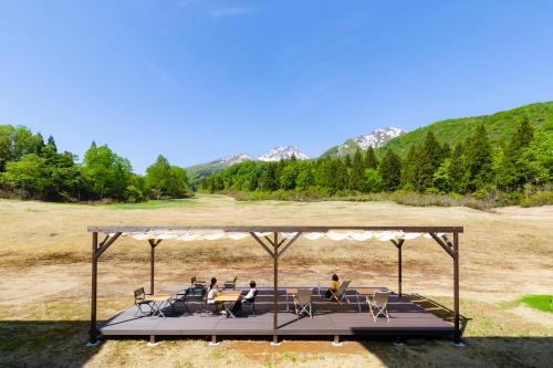 a group of people sitting at tables under a gazebo at Kyukamura Myoko in Myoko