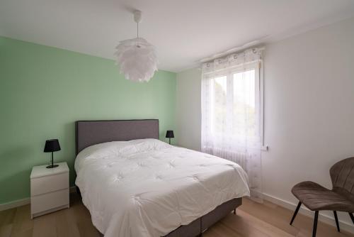 ein Schlafzimmer mit einem weißen Bett und einem Fenster in der Unterkunft Villa Mana - Sejour entre calme et modernite pour 6 in La Forêt-Fouesnant