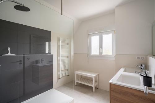 ein weißes Badezimmer mit einem Waschbecken und einem Spiegel in der Unterkunft Villa Mana - Sejour entre calme et modernite pour 6 in La Forêt-Fouesnant