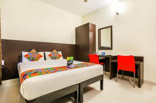 a bedroom with a bed and a desk with red chairs at FabHotel RMS Comforts Yeshwantpur in Bangalore