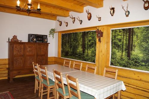 Fenyves Vendégház في Bábolna: غرفة طعام مع طاولة وكراسي ونوافذ