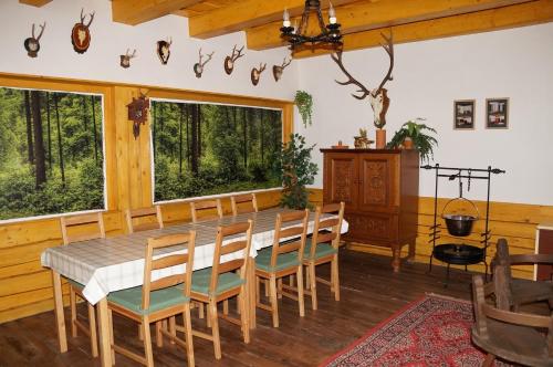 een eetkamer met een tafel, stoelen en ramen bij Fenyves Vendégház in Bábolna