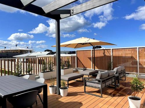 eine Terrasse mit Tischen, Stühlen und einem Sonnenschirm in der Unterkunft The Bright Home Torquay in Torquay