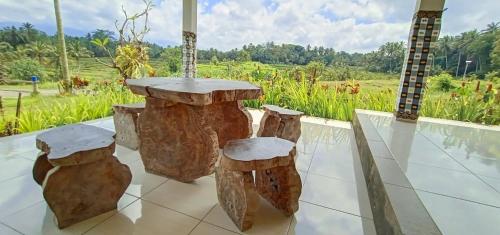 una mesa hecha de troncos con vistas a un campo en Celemanik Villa, en Tabanan