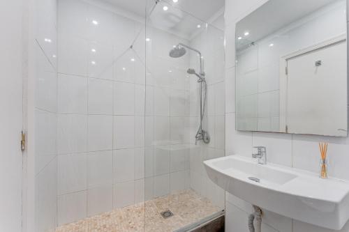 La salle de bains blanche est pourvue d'une douche et d'un lavabo. dans l'établissement Incredible Sea & Mountain View AirCon Front Line of Atlantic Ocean, à Puerto de Santiago