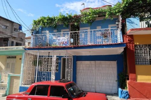 a red car parked in front of a blue building at Casa Mari y Santi Appartement 3 in Santiago de Cuba
