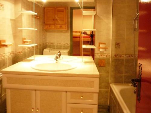 uma casa de banho com um lavatório, um espelho e uma banheira em Appartement Les Orres, 1 pièce, 4 personnes - FR-1-322-255 em Les Orres