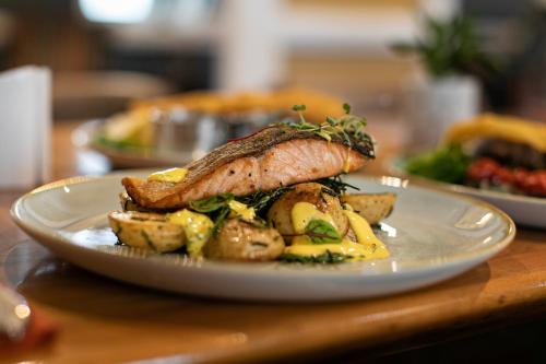 a plate with a fish and potatoes on a table at The Beaches Hotel and Spa in Prestatyn