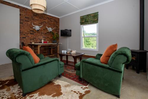 a living room with two green chairs and a brick wall at Springvale Farm in Nottingham Road