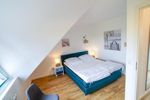 a bedroom with a blue bed and a chair at Ferienwohnung 11 "Gut Tossens" in Tossenserdeich