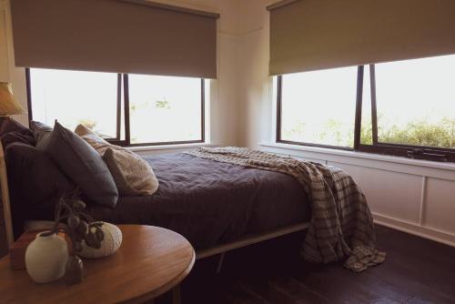 a bedroom with a bed and a table and windows at Quaint and intimate 1-bed seaside cottage in Bridport