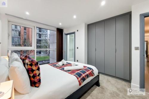 a bedroom with a large bed and large windows at Stylish Three Bedroom Apartment by London ExCeL in London