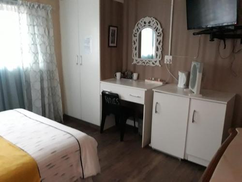 um quarto com uma cama, uma secretária e um espelho em Radies Bed and Breakfast em Cofimvaba