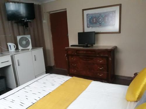 1 dormitorio con 1 cama y vestidor con TV en Radies Bed and Breakfast, en Cofimvaba