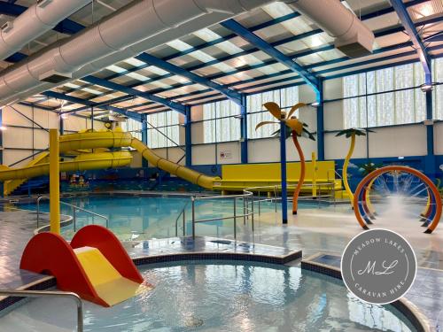 a swimming pool with a slide in a water park at Palm Grove 132 - pet friendly, WiFi, central heating, close to shops and beach - Meadow Lakes Caravan & Lodge Hire in Chapel Saint Leonards