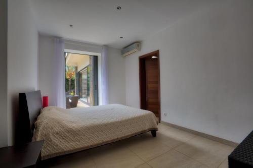 a bedroom with a bed and a sliding glass door at Balinea Villas in Pereybere