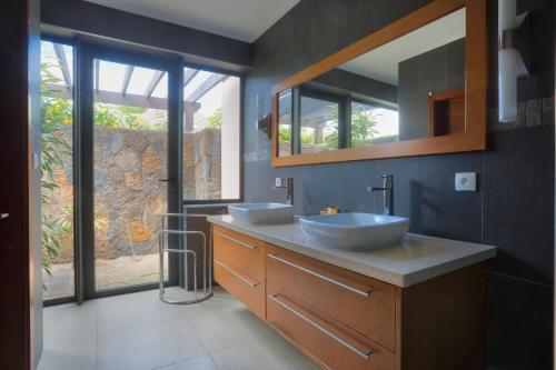 baño con 2 lavabos y ventana grande en Balinea Villas, en Pereybere