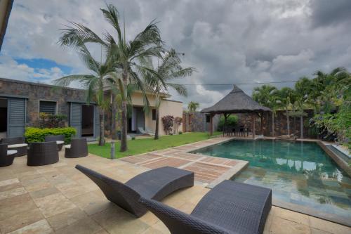 a swimming pool with chairs and a house at Balinea Villas in Pereybere