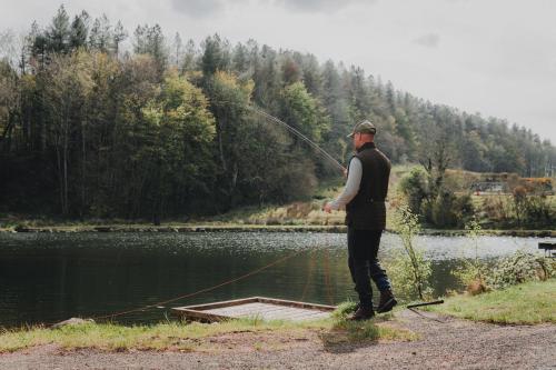 a man standing on a dock holding a fishing rod at Waterfall Caves in Limavady