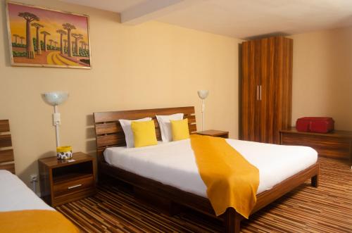 Cette chambre d'hôtel comprend 2 lits avec des oreillers jaunes. dans l'établissement Hotel Le Pousse Pousse, à Antananarivo