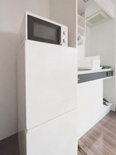 a microwave on top of a refrigerator in a kitchen at PINE TREE HOTEL in Hiroshima