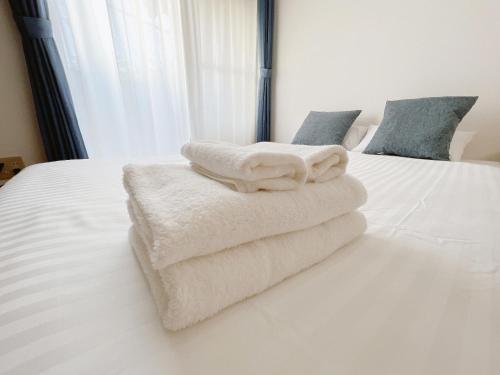 a pile of towels sitting on top of a bed at PINE TREE HOTEL in Hiroshima