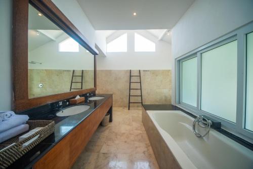 a bathroom with two sinks and a tub and a large mirror at Suzuki Villa Ketewel Beachfront in Ketewel