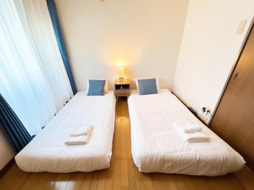 two beds in a small room with a window at PINE TREE HOTEL in Hiroshima