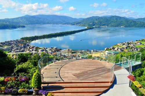a wooden boardwalk over a lake with a city at Taikyourou in Miyazu