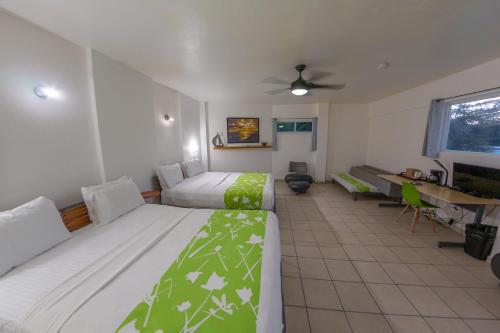 a bedroom with two beds and a desk and a desk at Casa Verde Hotel - Steps to the Beach, Pool, Restaurant & Bar in Rincon