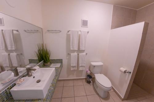 a white bathroom with a sink and a toilet at Casa Verde Hotel - Steps to the Beach, Pool, Restaurant & Bar in Rincon